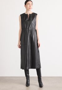 Schwarzes Leder-Midi-Kleid mit ärmellos Design, hohem Ausschnitt, tailliertem Bund und glatter Textur; präsentiert sich in einem maßgeschneiderten und minimalistischen Stil.
