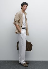 Beige Leinenjacke, weißes Hemd und lockere weiße Hose. Braune Schultertasche, olivfarbene Sandalen. Schlichte, neutrale Farbpalette, lässiges Design.