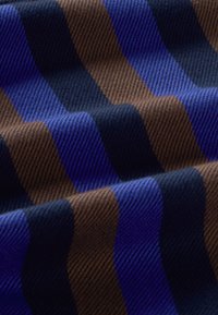Tejido tejido con rayas alternas en azul marino, azul real y marrón. La textura es suave con un ligero brillo.