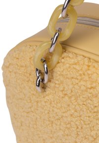 Borsa gialla texturizzata realizzata in un materiale morbido e soffice, con dettagli in morbida ecopelle e una maniglia in plastica chunky. Dettagli in metallo argentato evidenziati.