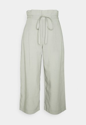 Pantalon large taille haute beige clair avec des plis à l'avant et une ceinture en tissu nouée en nœud à la taille.