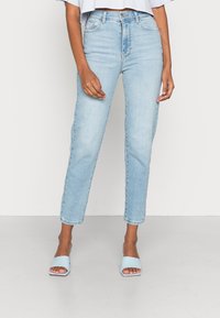 Ljust blå denimjeans med rak passform, femfickorsdesign och lätt urtvättad, i kombination med blåa tofflor.