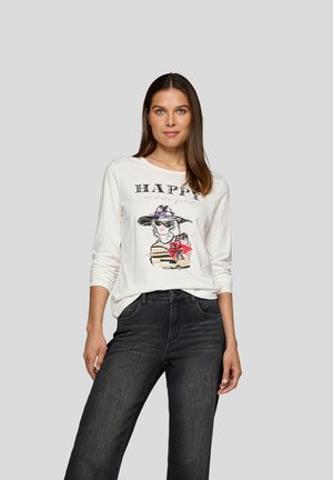 Langärmliges weißes T-Shirt mit einem grafischen Design einer Frau mit einem Hut, die eine Blume hält, kombiniert mit dunklen Jeans.