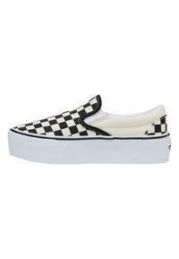 Zapatilla negra y blanca de cuadros con suela blanca, que presenta una parte superior de lona y acentos elásticos en los laterales para facilitar su uso.