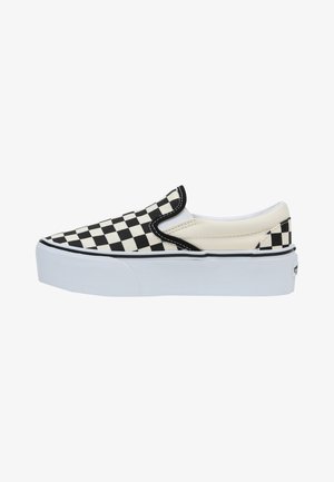 Zapatilla negra y blanca de cuadros con suela blanca, que presenta una parte superior de lona y acentos elásticos en los laterales para facilitar su uso.