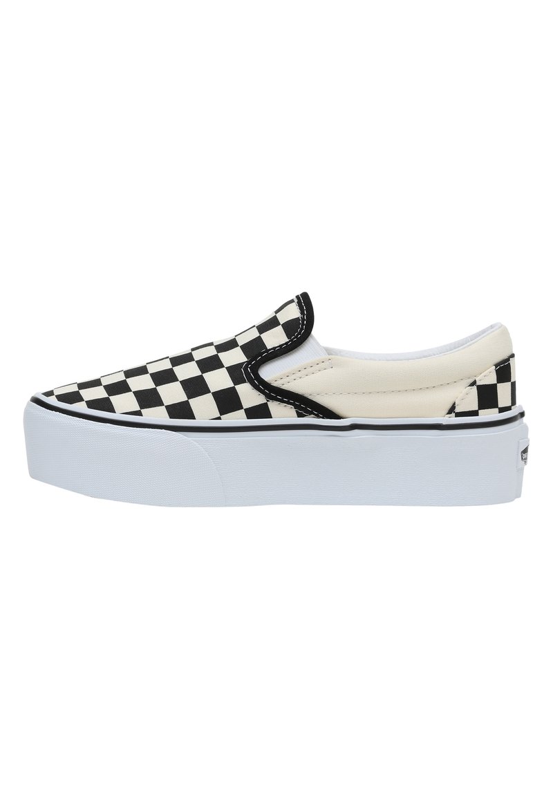 Zapatilla negra y blanca de cuadros con suela blanca, que presenta una parte superior de lona y acentos elásticos en los laterales para facilitar su uso.