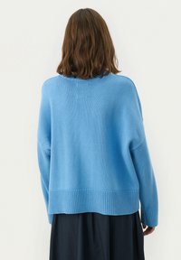Hellblauer, gestrickter Pullover mit lockerer Passform, geripptem Saum und langen Ärmeln. Glatte Textur, oversized Design. Keine sichtbaren Muster oder Hardware-Details.