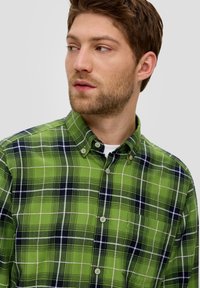 Green and navy plaid shirt with button-down collar, featuring white gridlines and smooth cotton texture. Classic fit with subtle details.