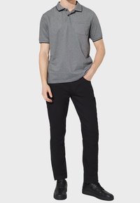 Grå polo skjorta med svart kant, korta ärmar och bröstficka, tillsammans med svarta byxor och svarta sneakers.