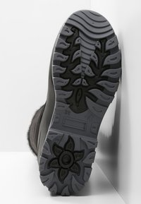 Černá podrážka boty s hlubokými drážkami a vzorem květin na protiskluzovém povrchu, vyrobená z gumy se šedým základem. Velikost označena jako 38.