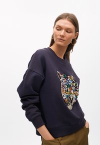 Sudadera azul marino de corte relajado, con un diseño de cara de leopardo colorido hecho de lentejuelas en la parte delantera y puños acanalados en el dobladillo.