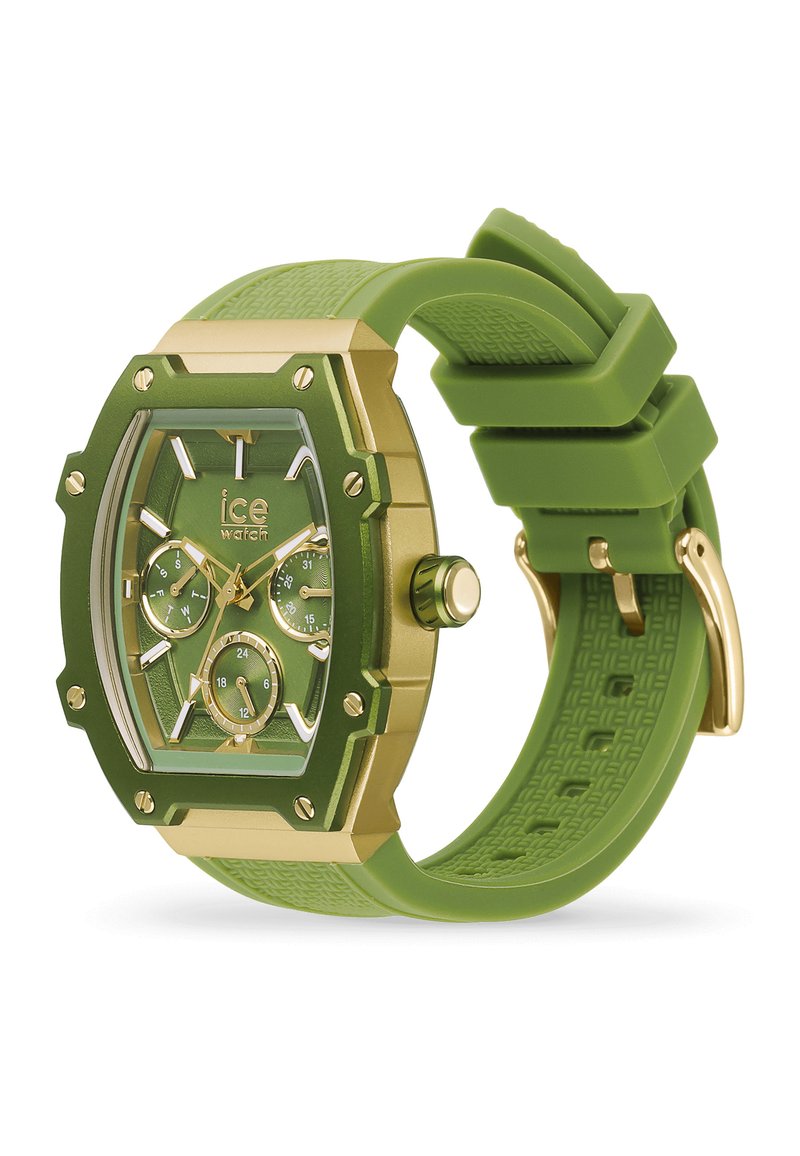 Montre analogique verte avec un cadran rectangulaire, des accents dorés, un bracelet en silicone texturé et plusieurs sous-dials pour la date et l'heure.