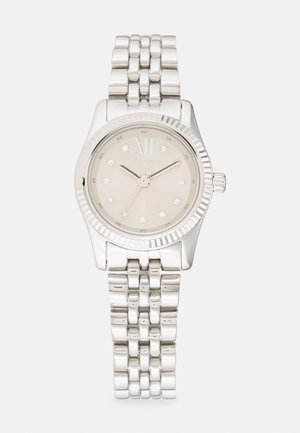 Stříbrné náramkové hodinky s kulatým pouzdrem, béžovým ciferníkem, diamantovými hodinovými značkami, dvanáctkou a spojeným kovovým náramkem s texturovaným povrchem.