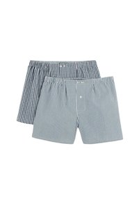 Une paire de boxeurs en tissu coton. L'un a un motif à carreaux sombres, l'autre présente des rayures verticales bleues et blanches. Chacun a un bouton sur le devant.