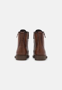 Stivali ankle in pelle marrone con texture, con zip laterali, tacco basso impilato e cuciture dettagliate, che presentano un motivo ispirato ai rettili.