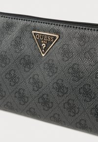 Czarny teksturowany portfel wykonany z syntetycznego materiału, zdobiony tłoczonymi wzorami oraz złotym trójkątnym logo z napisem "GUESS USA". Zapięcie na suwak.