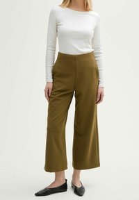 Olive green wide-leg pants with a high waist, made from soft fabric, paired with a fitted white long-sleeve top and black flats.