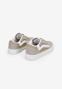 Zapatillas beige con acentos blancos, material de ante y textil, punta redondeada, suela plana de goma blanca y cordones en la parte delantera.