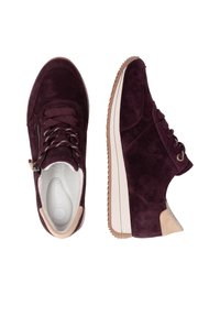 Paire de baskets en daim violet foncé avec des accents beige au talon, fermeture éclair latérale et semelle blanche, vues de dessus et de côté.