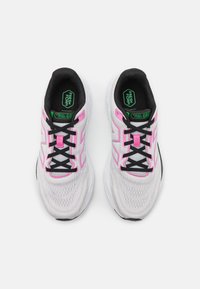 White running shoes with a mesh upper, accented by pink and green details, feature black laces and a classic shape designed for comfort.