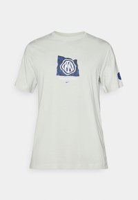 Ανοιχτό γκρι μπλουζάκι φτιαγμένο από βαμβάκι, με μπλε και μαύρο σχέδιο γραφικών που περιλαμβάνει το λογότυπο "Interazionale Milano" μπροστά.