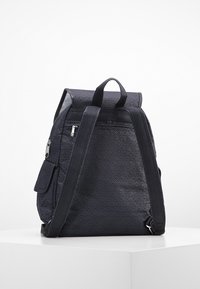 Czarny plecak z teksturowanej tkaniny o kształcie trójkąta, z regulowanymi ramiączkami, przednią kieszenią na zamek oraz uchwytem do łatwego przenoszenia.