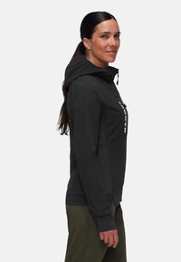 Schwarze Kapuzenjacke mit schlanker Passform, strukturierten Akzenten und prominentem Logo an der Seite. Weicher Stoff und verstellbare Kapuzendetails.