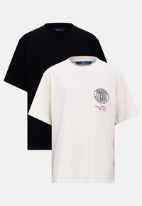 Two t-shirts: one black, one cream. Both have short sleeves and crew necks. Cream shirt features a graphic and red text on the chest.