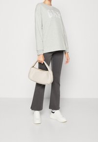 Jasnoszary sweatshirt z logo "GAP", ciemnoszare dopasowane spodnie, białe sneakersy oraz beżowa torebka teksturowana o zaokrąglonym kształcie.