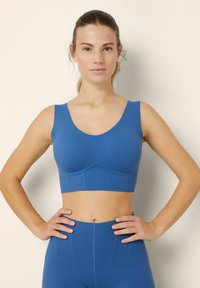 Reggiseno sportivo blu con spalline larghe, scollatura arrotondata e design senza cuciture. Materiale morbido ed elastico con leggera imbottitura.
