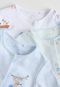 Trois gilets pour bébé : blanc avec impression de bateau et de lapin, bleu clair avec lapin brodé, et bleu pâle avec texture subtile et boutons.
