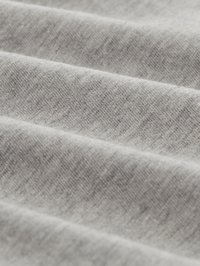 Tessuto grigio chiaro morbido con una fine trama a maglia mostrato in pieghe delicate e in dettaglio ravvicinato.