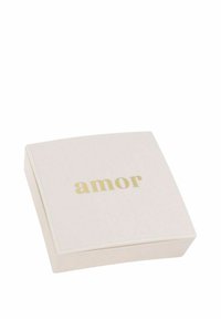 Kvadratisk, ljusrosa låda med en slät yta. Ordet "amor" är präglat i guld. Kanterna är rundade, vilket ger ett mjukt intryck.