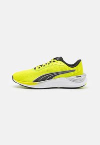 Zapatillas de correr de color amarillo brillante con un upper texturizado, detalles en negro, cierre de cordones y una suela blanca acolchada. Presenta un detalle en la suela exterior de color plateado.