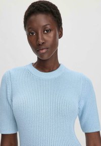 Lichtblauw gebreid top met een ronde halslijn en korte mouwen. De stof heeft een gestructureerde weving en een aansluitende pasvorm.
