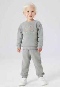 Szary dres bawełniany z fakturowanym nadrukiem samochodu i napisem "COOL CAR", zestawiony z białymi trampkami, na tle jednolitego tła.