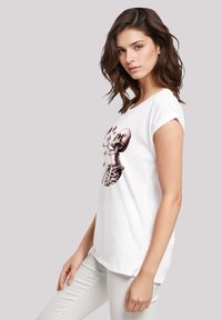 Weißes Baumwoll-T-Shirt mit kurzen Ärmeln; mit einem grafischen Druck eines Skeletts und eines Herzens. Glatte Textur, lockere Passform, abgerundeter Saum.