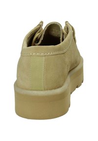 Scarpa scamosciata di colore beige con una superficie liscia, dotata di una suola imbottita, forma arrotondata e lacci elastici per una calzata sicura.