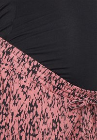 Top preto ajustado combinado com uma saia cor-de-rosa com um padrão abstrato preto, com cintura elástica e detalhes de cordão.