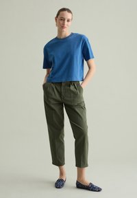 Blauwe katoenen cropped t-shirt, olijfgroene tapered broek en gestreepte marineblauwe instapschoenen. Eenvoudig ontwerp met een relaxte pasvorm.