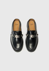 Black leather loafers with a silver chain accent, smooth texture, contrasting sole stitching, and branded footbed label.