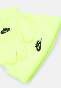 Neon žute rukavice i odgovarajući šal od mekog pletenog materijala, s crnim Nike logotipima na oba artikla.