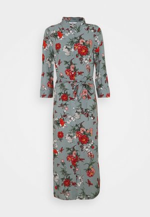 Robe chemise verte à manches longues, avec ceinture à la taille et imprimé floral rouge, blanc et rose.