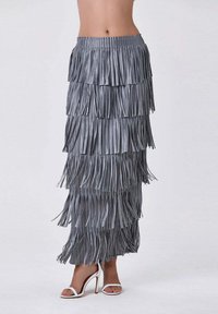 Jupe maxi grise à franges, présentant des panneaux superposés et une taille ajustée. Fabriquée dans un matériau léger, elle arrive à la cheville.