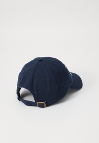 Căciulă de baseball din bumbac de culoare bleumarin, cu o margine curbată, curea ajustabilă la spate și un buton din material pe partea de sus. Design simplu cu aerisiri.