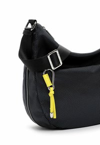 Borsa in tessuto nero con texture, dalla forma curva, dotata di una ampia tracolla nera, hardware in argento e un'etichetta di accento gialla. Chiusura con zip sul lato.