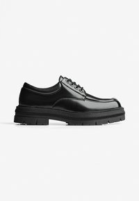 Scarpe in pelle nera con punta rotonda, design strutturato, suola in gomma spessa e chiusura con lacci. Presentano cuciture dettagliate lungo i bordi.