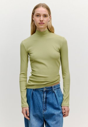 Geribbelde, lange mouwen turtleneck in lichtgroen, slimfit ontwerp. Gecombineerd met losse, hoge taille blauwe denim jeans. Minimalistische stijl.