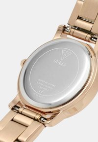 Kuldtooni roostevabast terasest kell hõbedaste tagaküljega, millel on sile pind ja poleeritud viimistlus, showcasing veekindluse detailid.