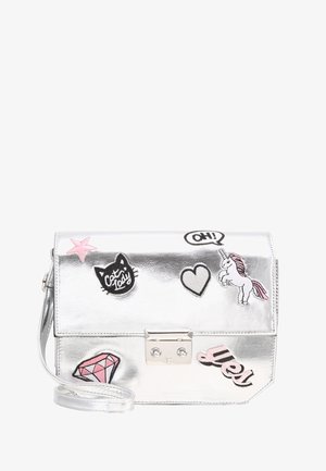 Srebrna torebka na pasku z naszywkami: różowa gwiazda, czarna głowa kota z napisem „cat lady”, serce, jednorożec, różowy diament oraz napis „yes!”.